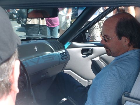 2000 Ford Crown Victoria - The interior of a 1993 Ford Mustang, a man seated inside and a prominent Mustang emblem on the dashboard.