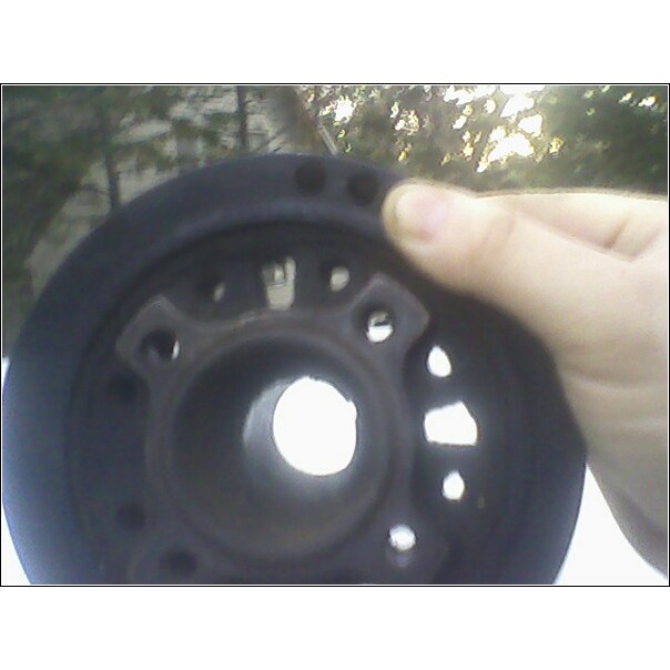 Pulley held by hand, showing mounting holes and outer edge