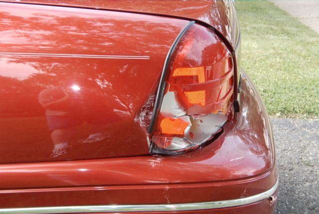 Close-up of a damaged red car's rear passenger side taillight and fender