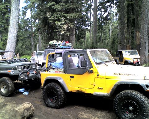 2005 Jeep Wrangler - A yellow Jeep Wrangler TJ with no top, a yellow roll bar, half doors and a 'Northridge 4x4' decal on the hood sits loaded with camping gear…