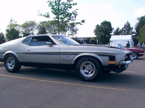 1998 Ford Taurus - A silver 1971 Ford Mustang Mach 1 is parked at an outdoor event, with another car visible in the background.