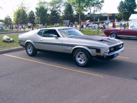 1998 Ford Taurus - Silver 1971 Ford Mustang Mach 1 with black hood stripes at a car meet, red convertible visible.