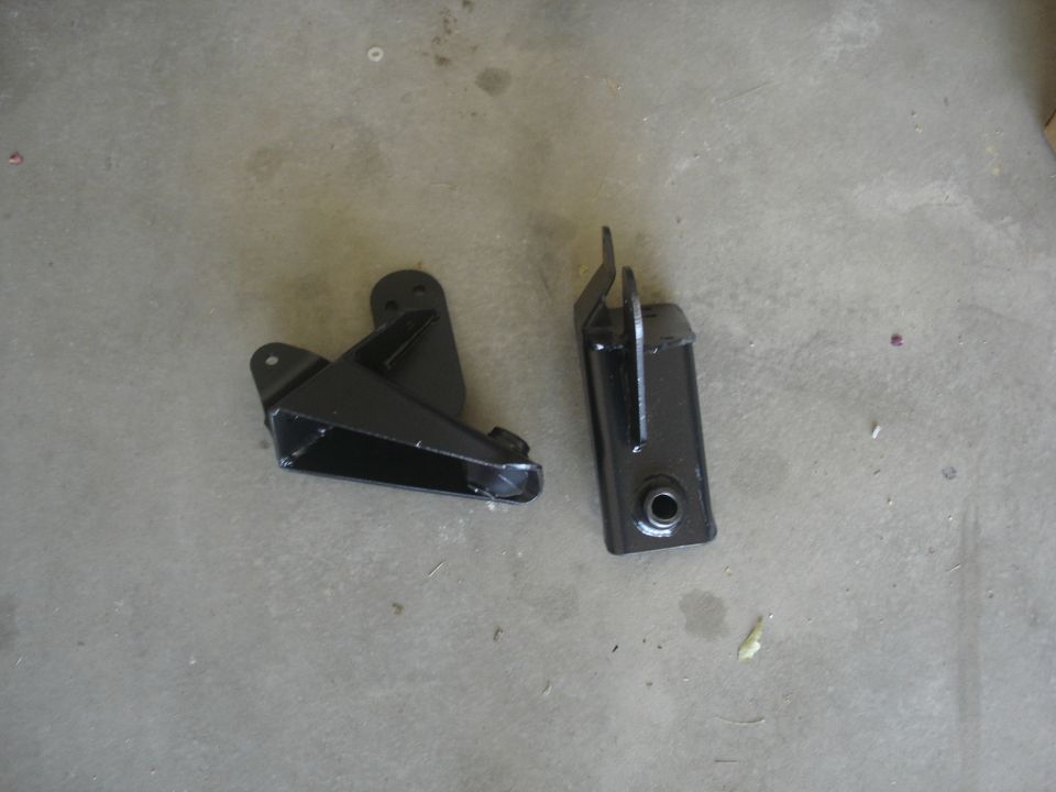 Two black metal brackets on a concrete floor.