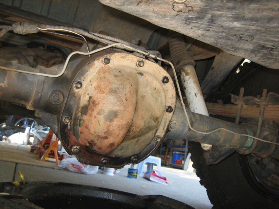 Underside of a vehicle showing a differential, brake lines, shock, leaf springs, and tire.