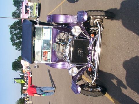 1998 Ford Taurus - A custom purple hot rod with a blue convertible top is displayed at an outdoor event, with a person standing next to it.