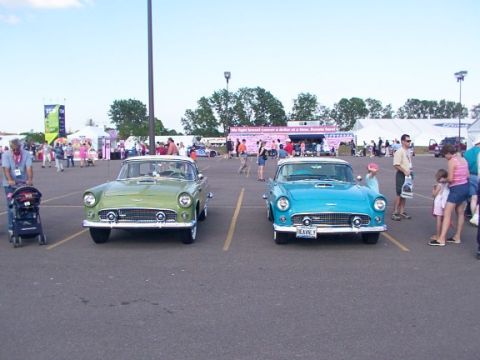 1998 Ford Taurus - Two classic Ford Thunderbirds, one green and one blue, are displayed at an outdoor event.
