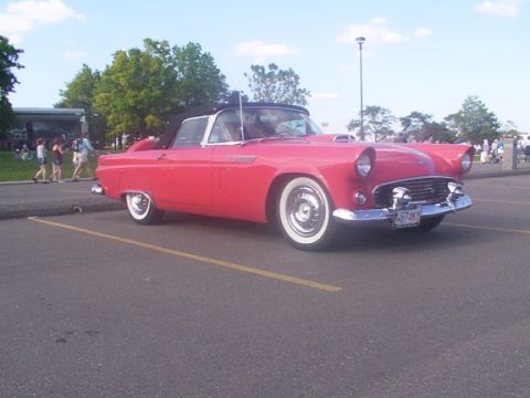 1998 Ford Taurus - A classic red convertible with whitewall tires is parked in a lot on a sunny day.