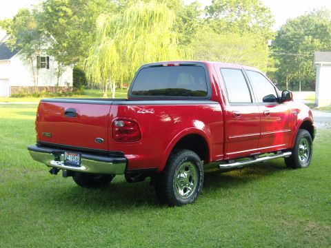 2007 Ford Mustang - Photograph of a red Ford F-150 crew-cab pickup parked on a lawn near houses.
