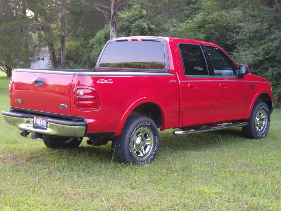 Red Ford F-150 SuperCrew 4x4 pickup, passenger-rear three-quarter view