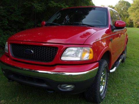2007 Ford Mustang - Close-up photograph of the front end of a red Ford F-150 pickup showing grille and headlight.
