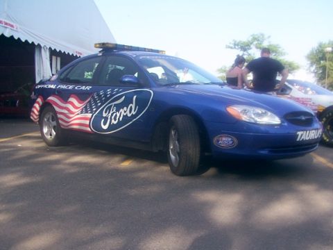 1998 Ford Taurus - A blue Ford Taurus pace car with American flag graphics is seen at an event.