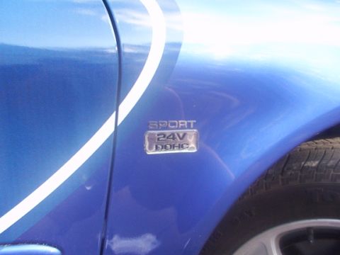 1998 Ford Taurus - Close-up of a blue car's fender showing a "SPORT 24V DOHC" emblem.