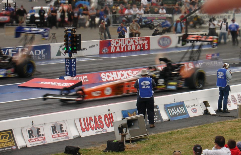 Drag racing cars on a track with a green light on the drag tree.