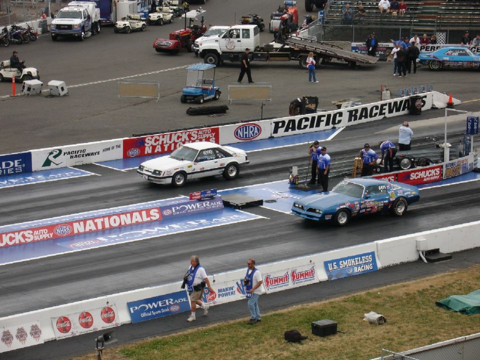 White Fox-body Mustang and blue Firebird staged at Pacific Raceways starting line