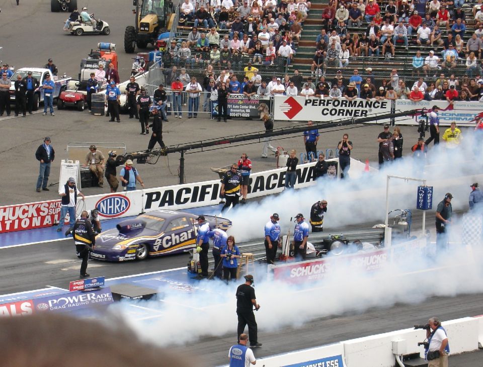 Charter funny car on the Pacific Raceways starting line amid tire smoke at NHRA event