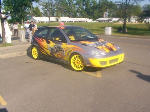 1998 Ford Taurus - This customized hatchback features a distinctive Hot Wheels theme with flame graphics and bright yellow wheels.