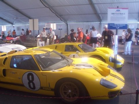 1998 Ford Taurus - Two classic Ford GT40 race cars are displayed under a tent, with spectators milling around.