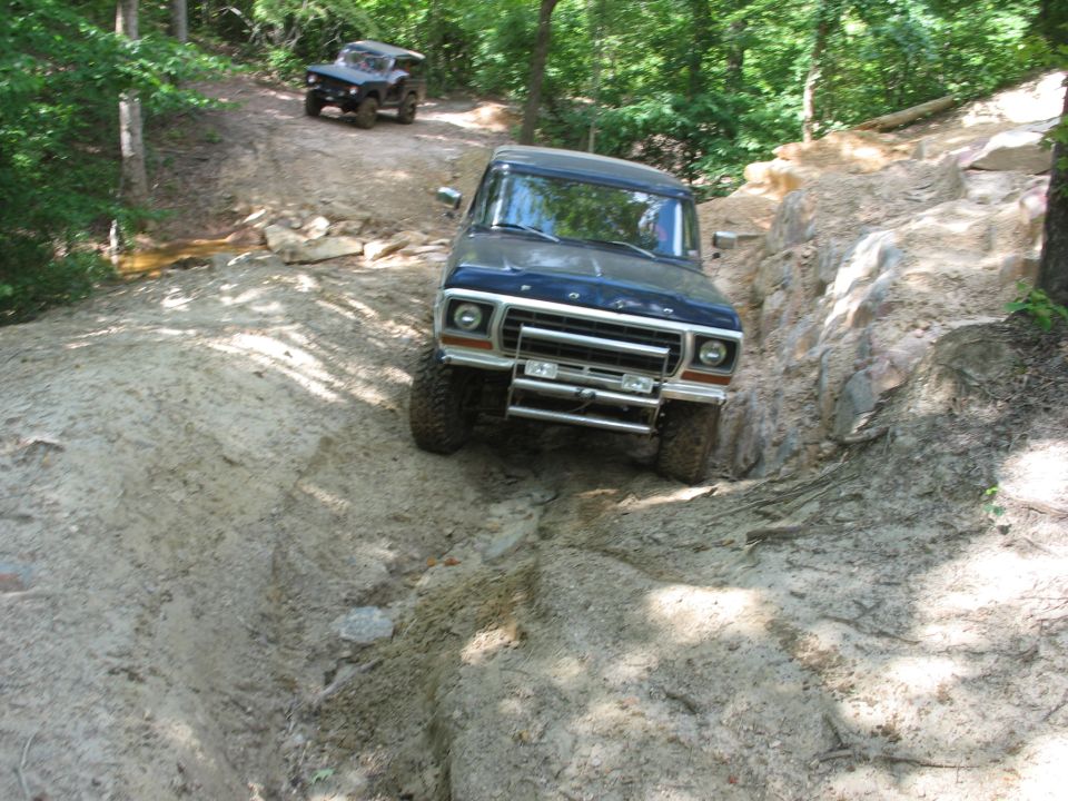 Ford Bronco climbing a steep rocky embankment on a forest trail