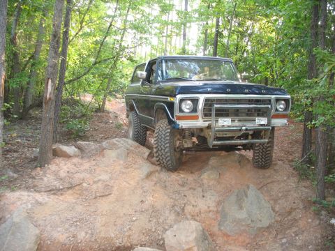 1978 Ford Bronco - This 1978 Ford Bronco is shown off-roading on a dirt path surrounded by trees.