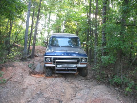 1978 Ford Bronco - A blue 1978 Ford Bronco navigates a muddy, wooded trail.