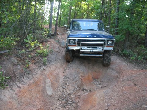 1978 Ford Bronco - 1978 Ford Bronco navigates a challenging off-road trail with steep inclines and loose dirt.