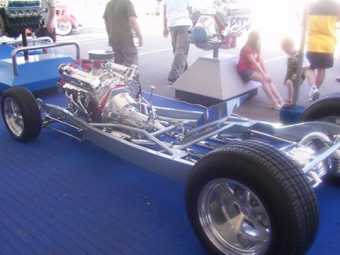1998 Ford Taurus - A custom hot rod chassis and engine are displayed on a blue carpeted surface.