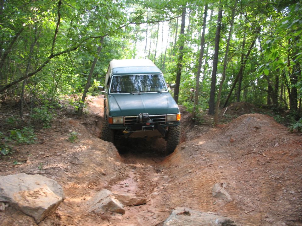 Green SUV with a winch on a muddy forest trail, front view