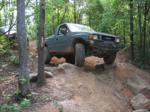 1978 Ford Bronco - An Isuzu pickup navigates a rocky off-road course, with another vehicle following behind on the trail.