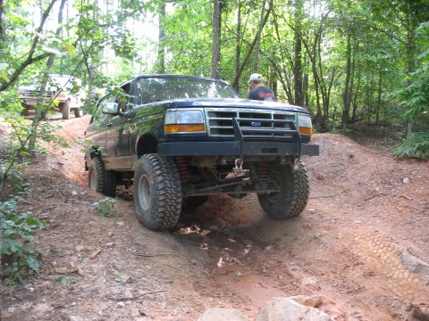 1978 Ford Bronco - Modified Ford Bronco tackles an off-road trail with another vehicle following in the background.