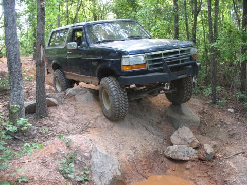 1978 Ford Bronco - This SUV navigates a challenging rocky terrain on a wooded trail.