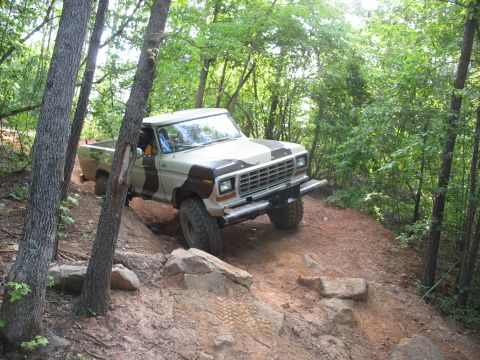 1978 Ford Bronco - This pickup truck, likely a 1979 model, navigates a rocky, wooded trail.