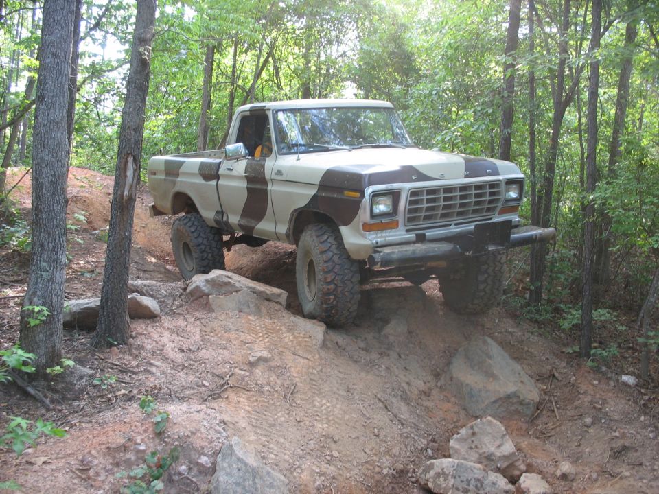 Ford pickup truck with camouflage paint climbing a rocky trail