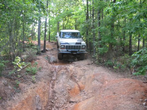 1978 Ford Bronco - The truck navigates a challenging off-road path with water and rocks.