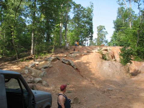 1978 Ford Bronco - Off-road trail scene with a parked vehicle and people navigating the terrain.