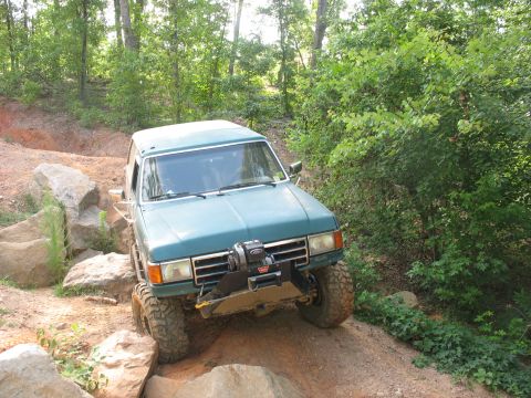 1978 Ford Bronco - Teal SUV navigates a rocky off-road trail.