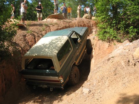 1978 Ford Bronco - 1978 Ford Bronco tackles a challenging off-road obstacle, with onlookers observing the action.