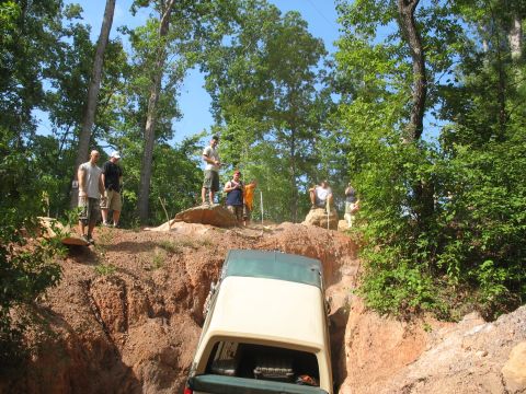 1978 Ford Bronco - A group of people watch as a 1978 Ford Bronco navigates a challenging off-road obstacle.