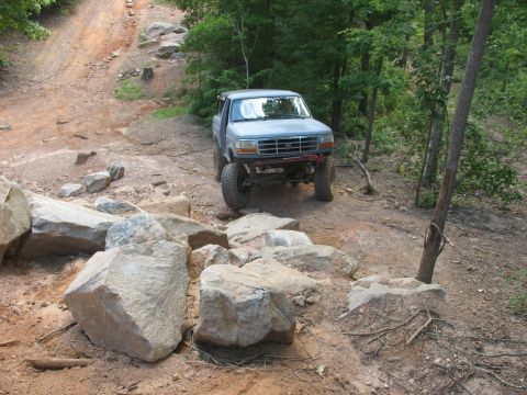 1978 Ford Bronco - A modified 1992 Ford F-150 navigates a challenging rocky terrain on an off-road trail.