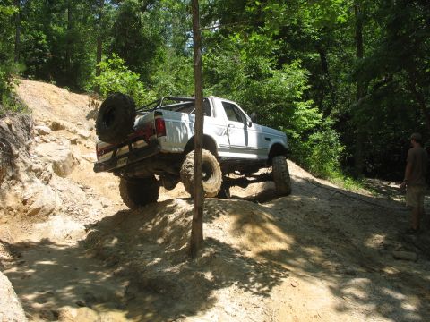 1978 Ford Bronco - This modified SUV is navigating a challenging off-road trail with steep inclines and rocky terrain.
