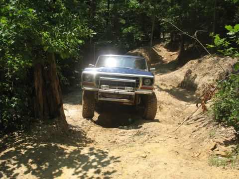 1978 Ford Bronco - This 1978 Ford Bronco navigates a challenging off-road trail surrounded by dense forest.