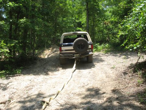 1978 Ford Bronco - Ford Bronco stuck in the mud, being pulled out with a strap.