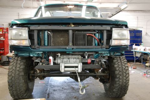 1996 Ford Bronco - The front of a teal Ford F-Series truck is shown with the grille removed, revealing the radiator and a winch.