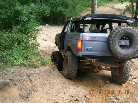 1991 Ford F-150 - A modified Ford Bronco navigates a challenging off-road trail with steep inclines.