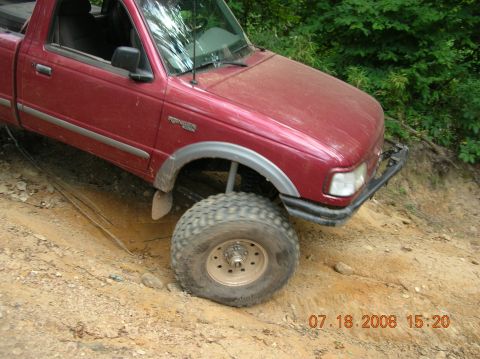 1991 Ford F-150 - This red pickup truck appears to be a Ford Ranger, not a 1991 Ford F-150, navigating an off-road trail.