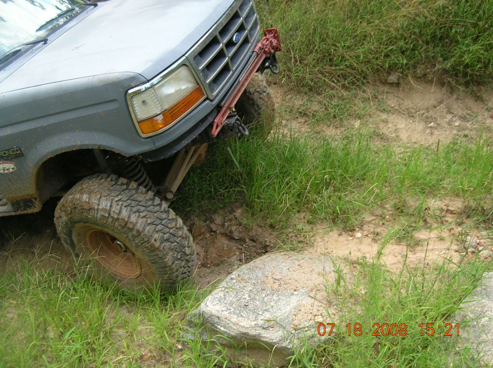 Gray 1991 Ford F-150 driving off-road, front tire on a rock