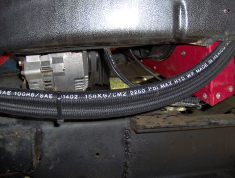 1978 Ford Bronco - Close-up view of an automotive alternator and a braided hose with pressure and specification markings.