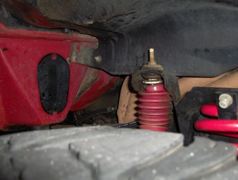 1978 Ford Bronco - Undercarriage view shows a red shock absorber and related suspension components, with a tire in the foreground.