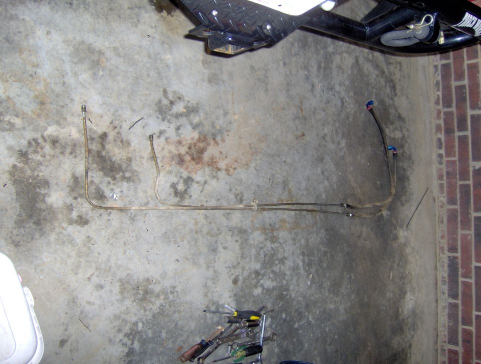 Two metal fuel lines with blue connectors on a concrete floor