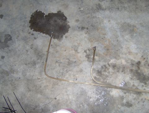 1978 Ford Bronco - Metal brake lines on a concrete floor, possibly from a vehicle repair.