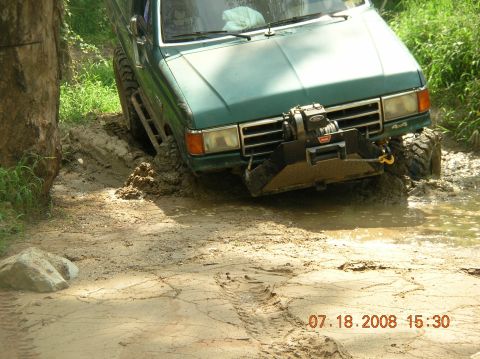 1991 Ford F-150 - A green 1991 Ford F-150 navigates a muddy trail, its front tires deep in the mire.